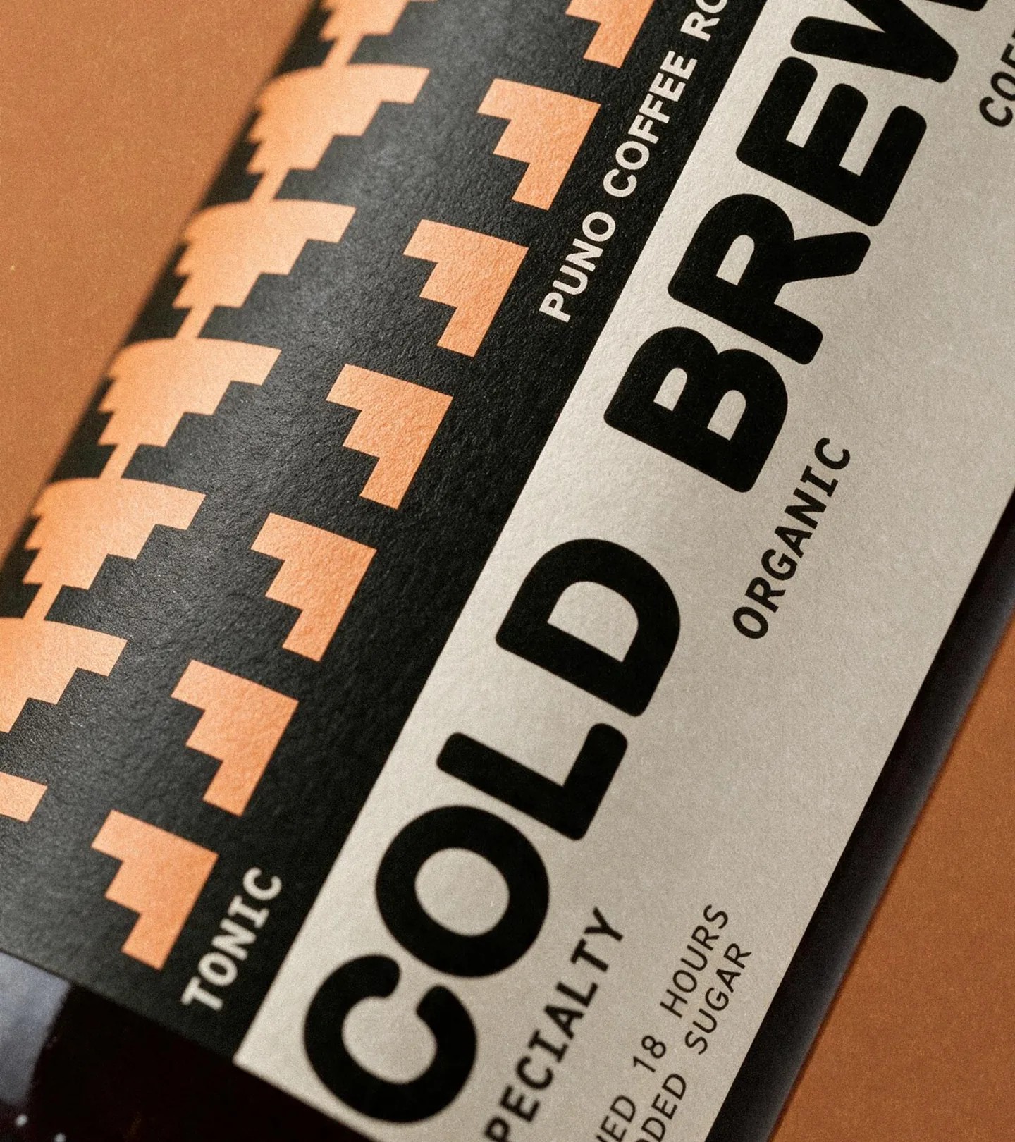 Close-up of the PUNO Coffee cold brew bottle label with peach-and-black pyramid pattern