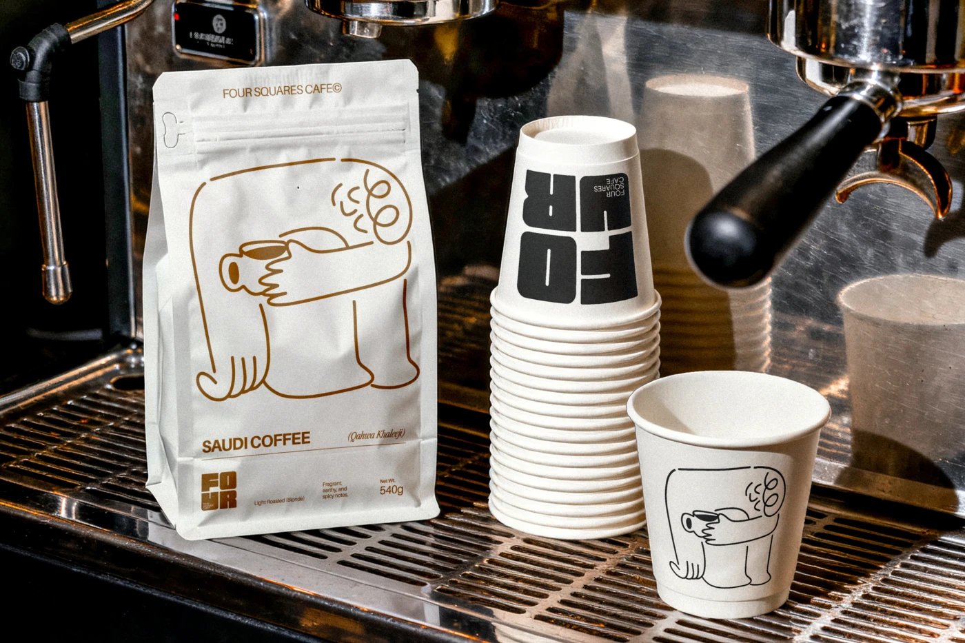 Four Squares Cafe coffee bags and branded takeaway cups at the machine