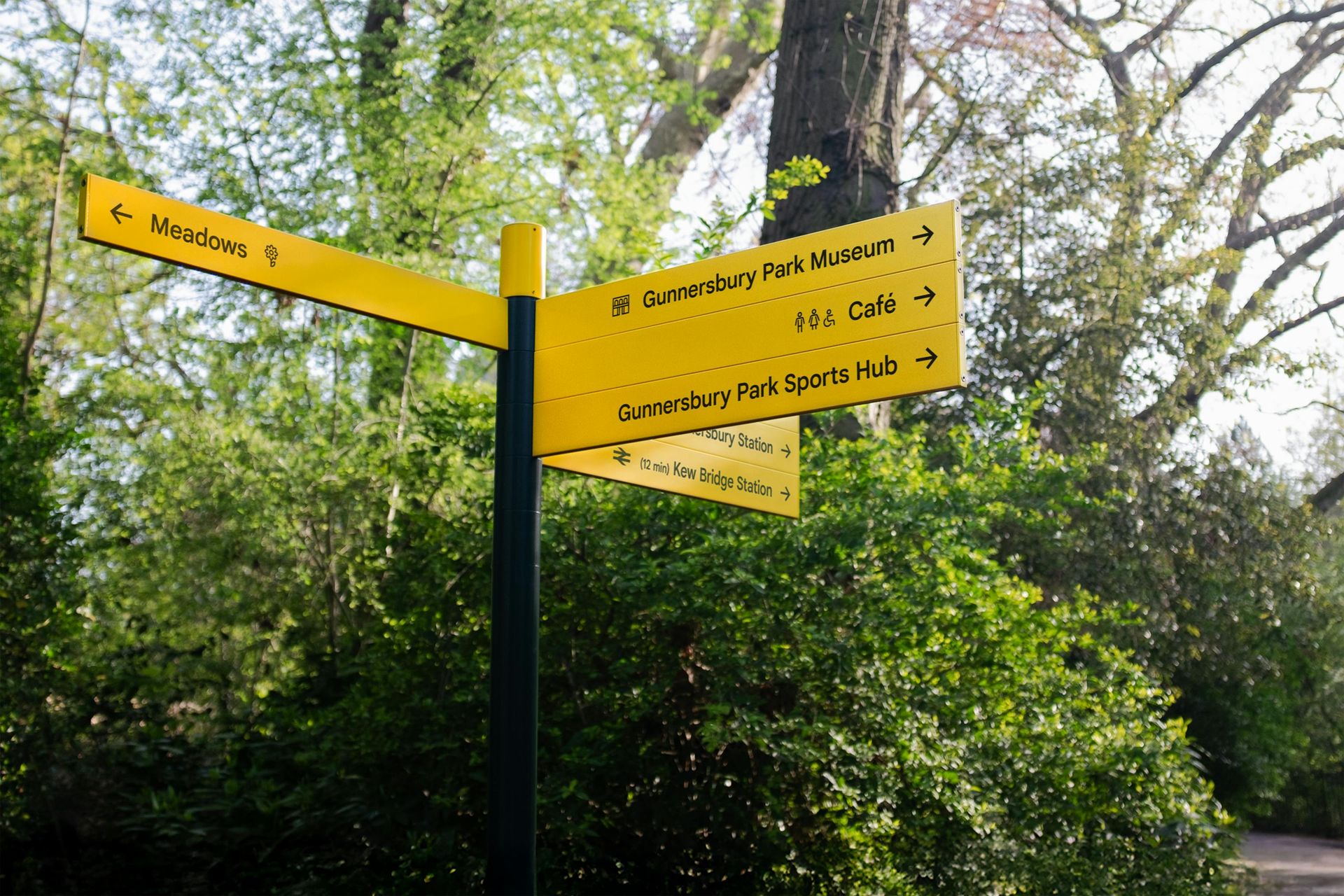 Yellow fingerpost wayfinding sign in Gunnersbury Park