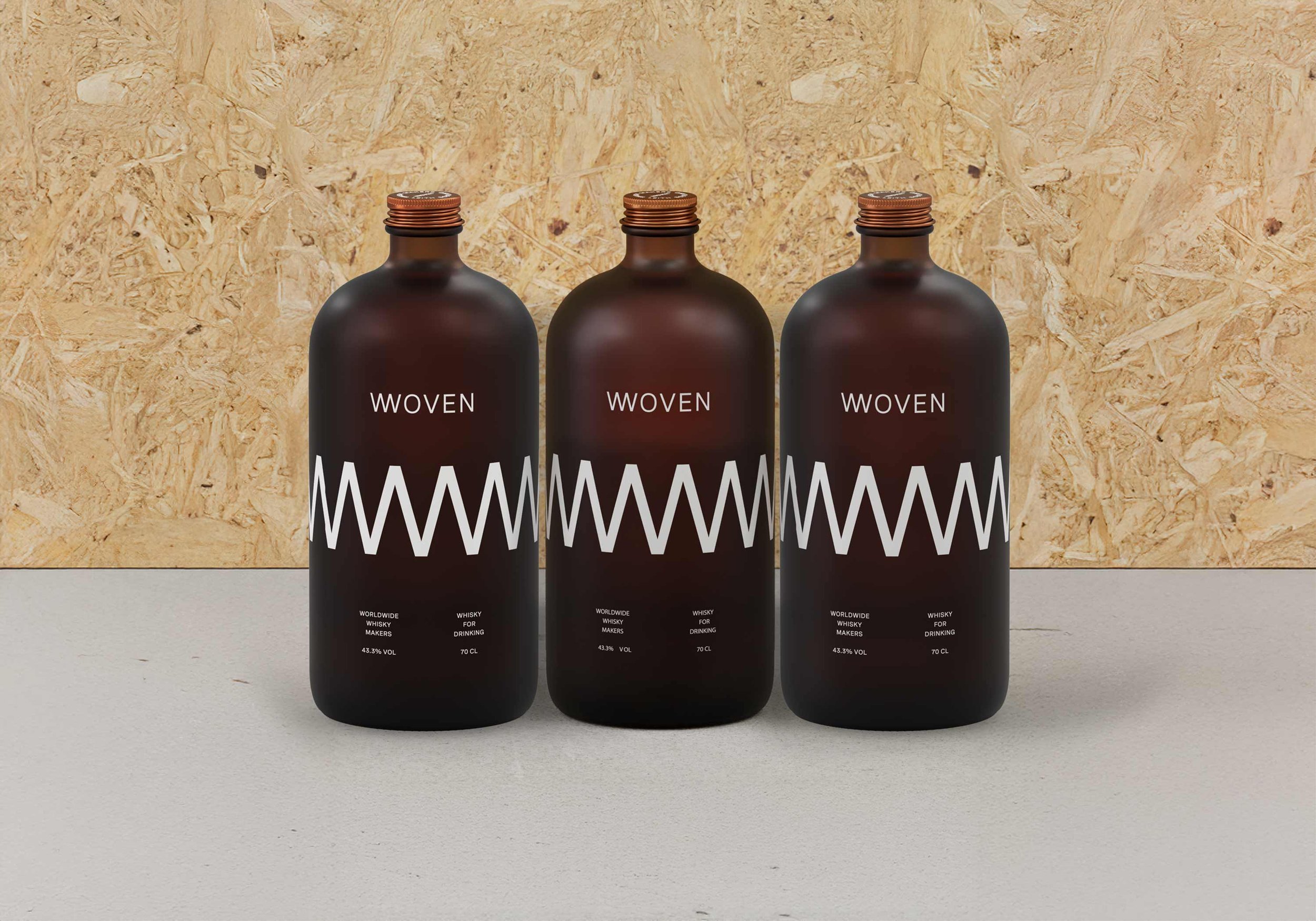 Three frosted Woven bottles with a wide white zigzag band around the glass, against a chipboard wall.