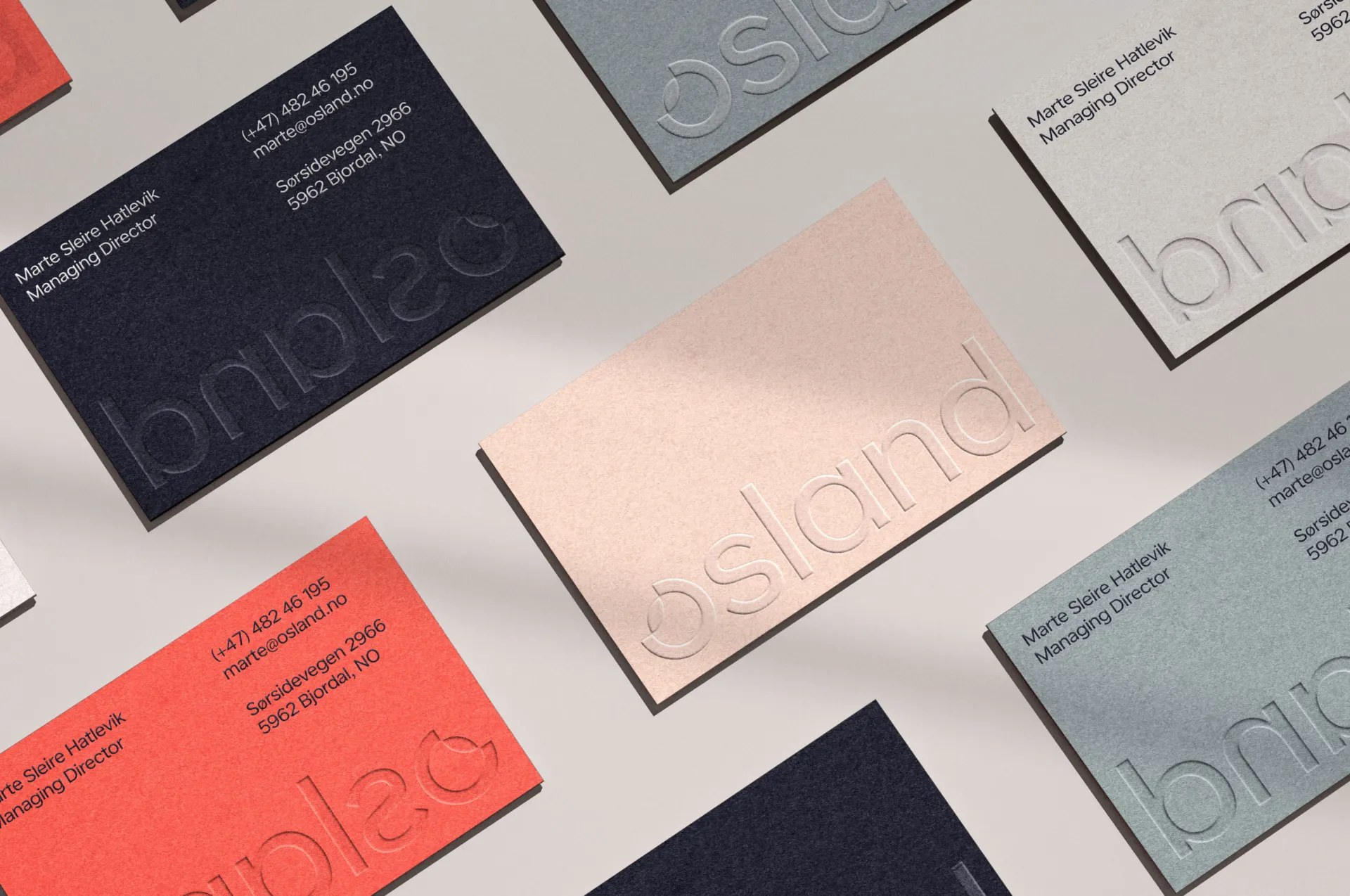 Osland business cards in coral, sand and dark blue with the blind-embossed lowercase wordmark