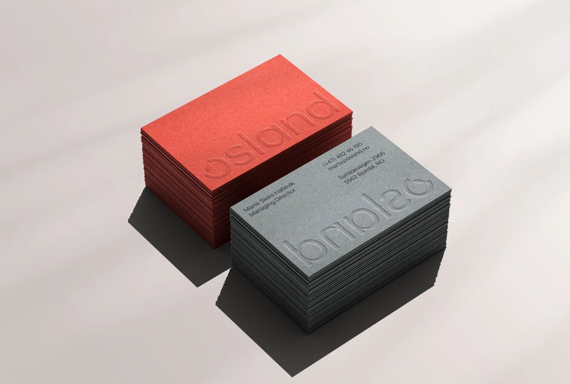 Stacks of Osland cards showing the embossed wordmark on coral and grey stocks
