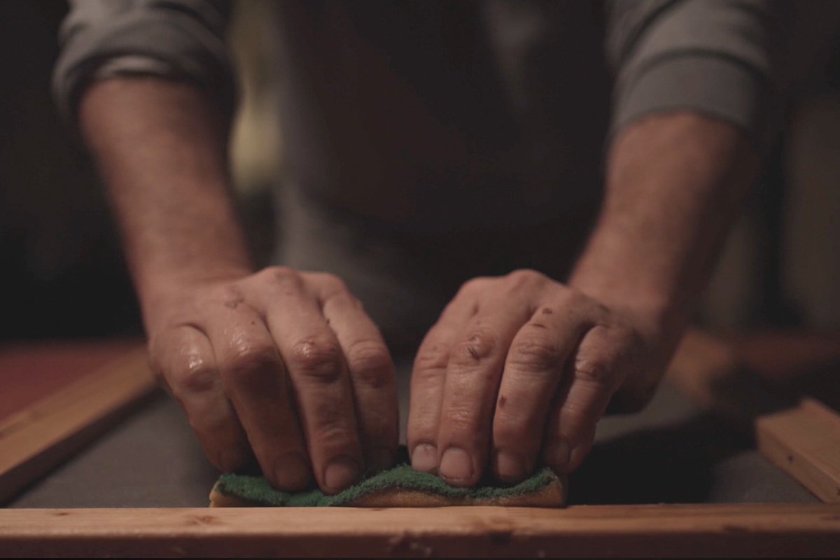 Hands pressing the sediment pulp into a rectangular frame to form the label paper