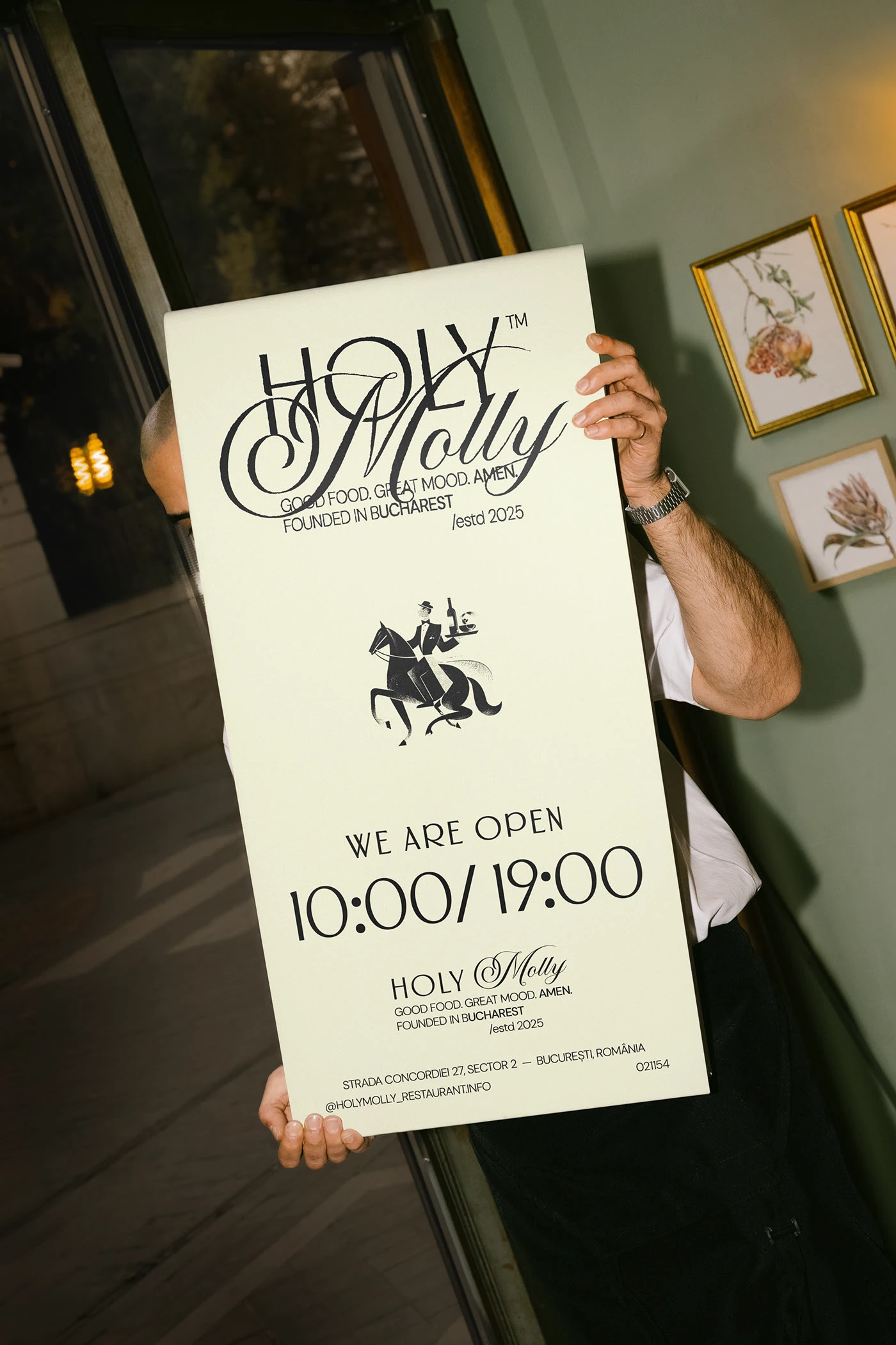Person holding tall Holy Molly poster card in black-and-white printed on cream stock — restaurant brand identity