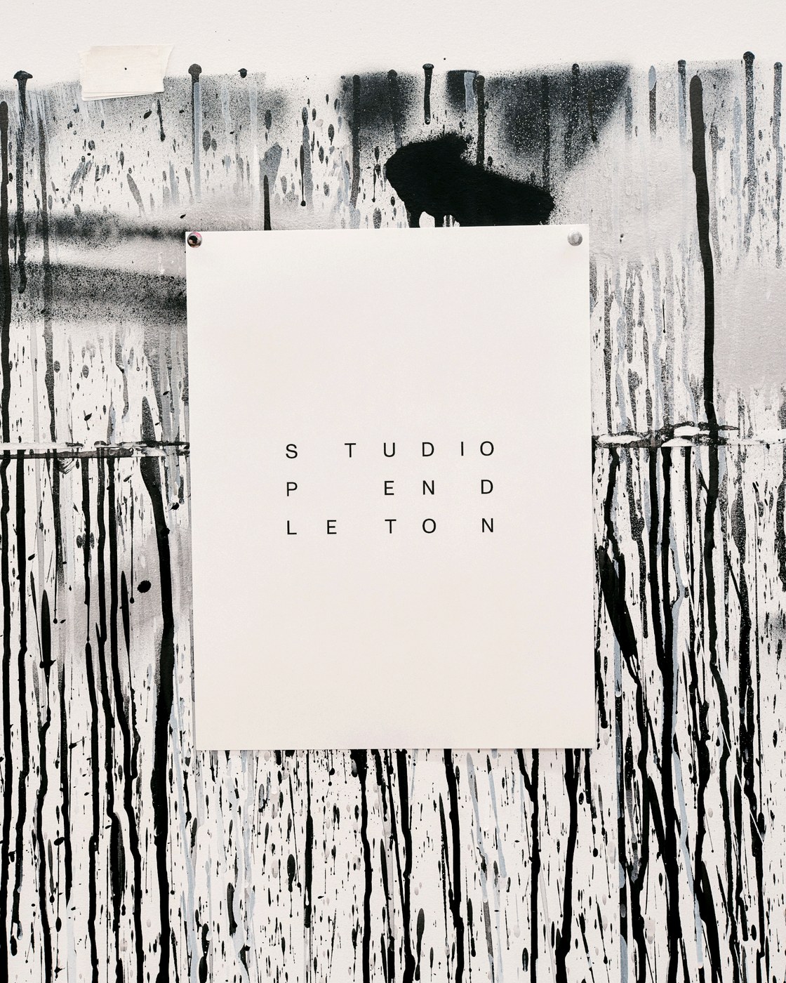 Studio Pendleton primary typographic identity mark on exhibition poster against paint-splattered wall by SAVVY STUDIO