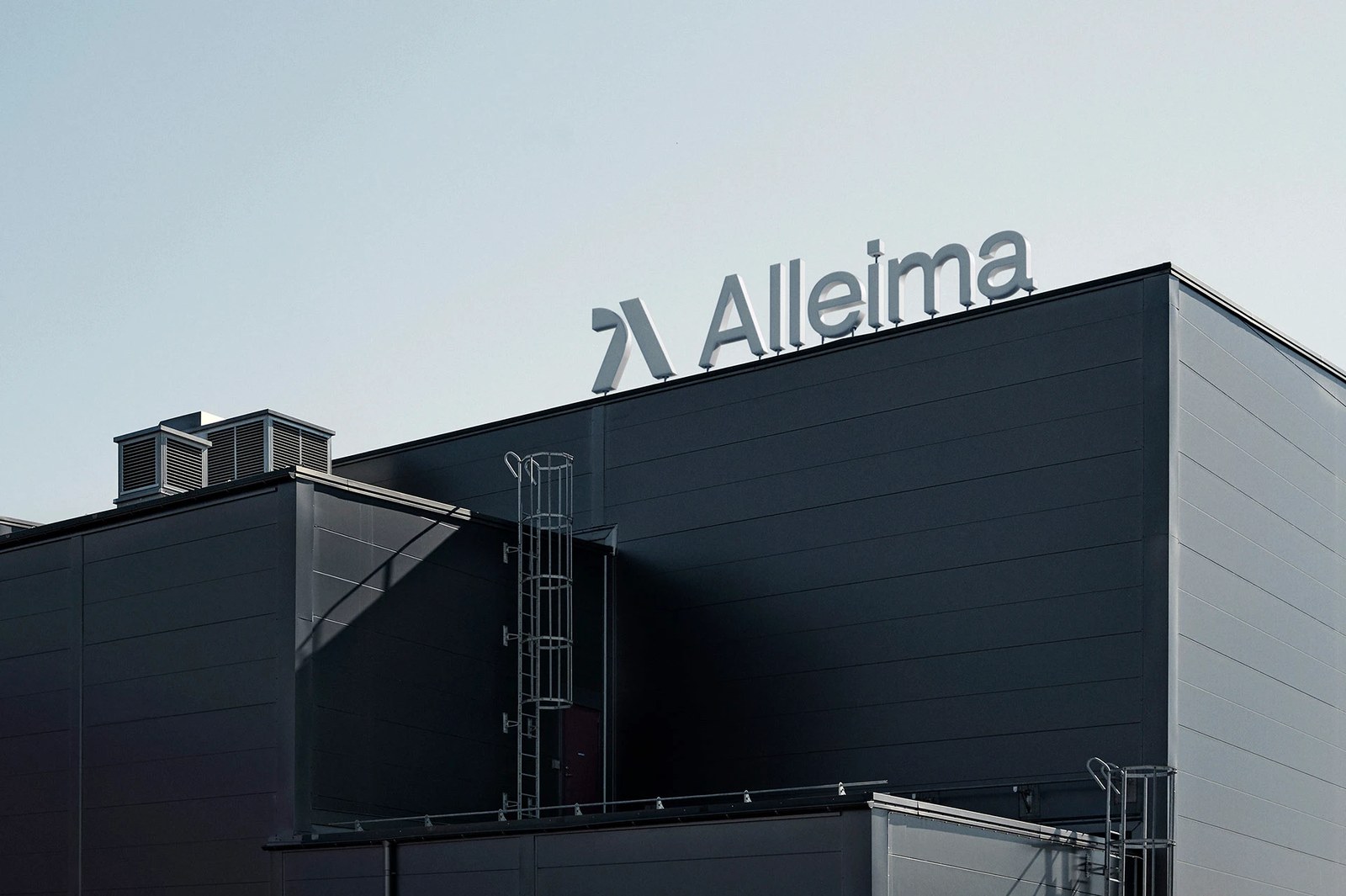 Exterior architectural signage of the Alleima logo mounted on a dark steel industrial facility roof