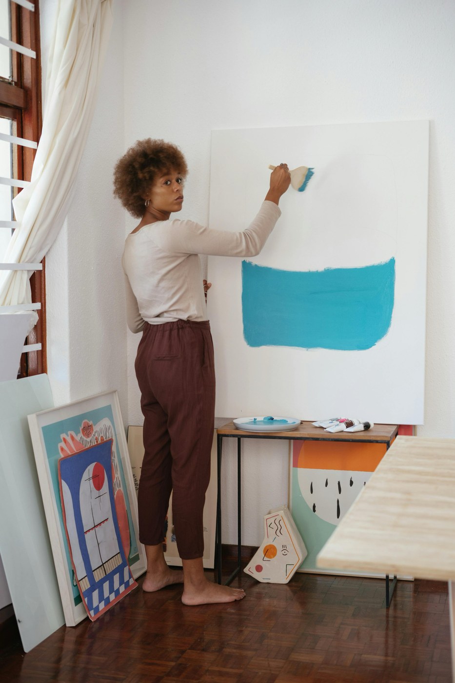 Editorial documentary portrait of independent artist working in her studio painting on canvas