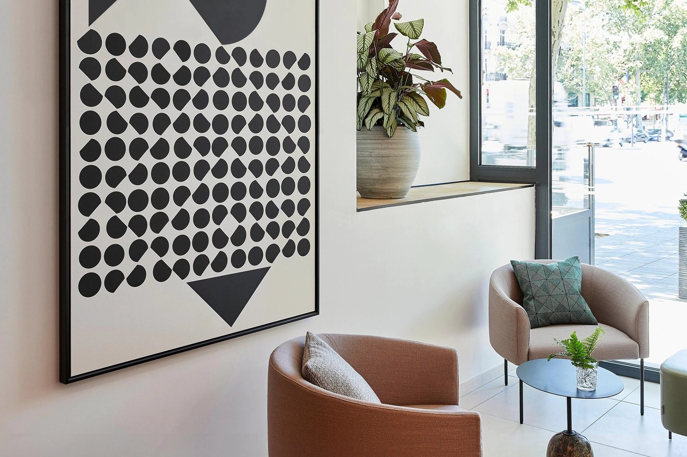 Framed Victor Vasarely inspired op-art geometric artwork installed above green velvet banquette seating at Crowne Plaza Paris République by Marçal Prats