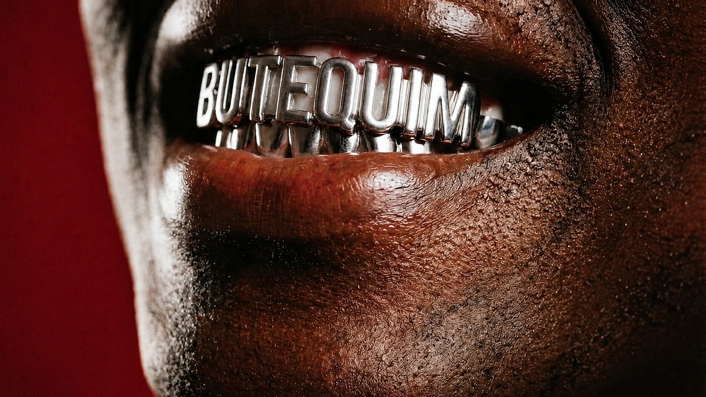 Macro detail of custom silver dental grillz spelling BUTEQUIM for brand identity by Estúdio Lippi