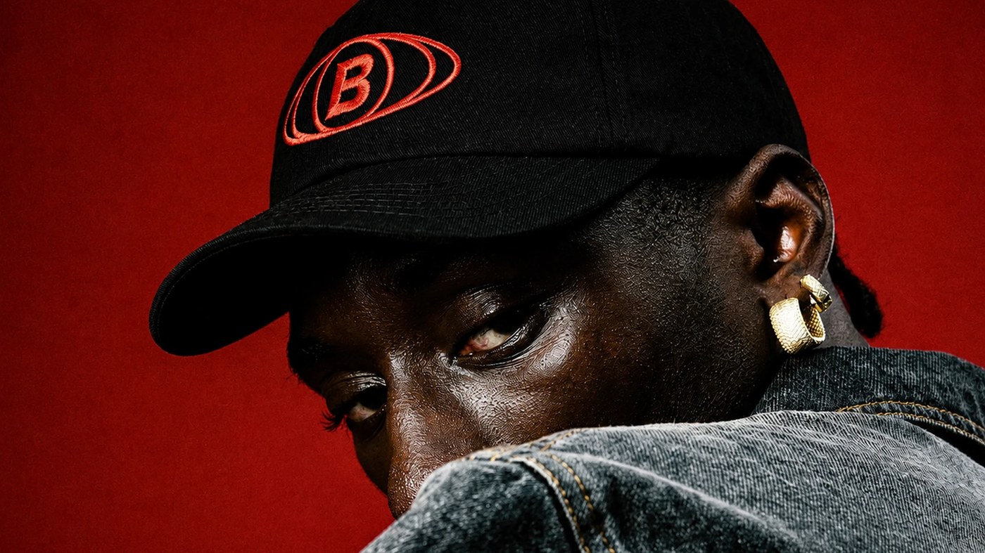 Portrait of person wearing black cap embroidered with red Butequim oval monogram in brand identity by Estúdio Lippi