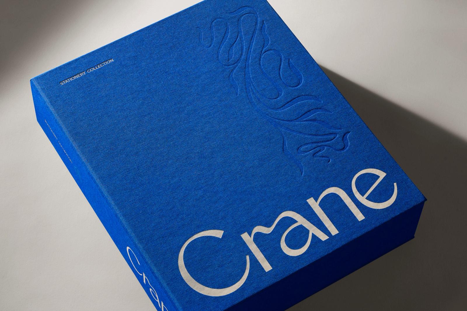 Royal blue cloth-bound Crane stationery keepsake box with blind-debossed crest and serif wordmark by COLLINS