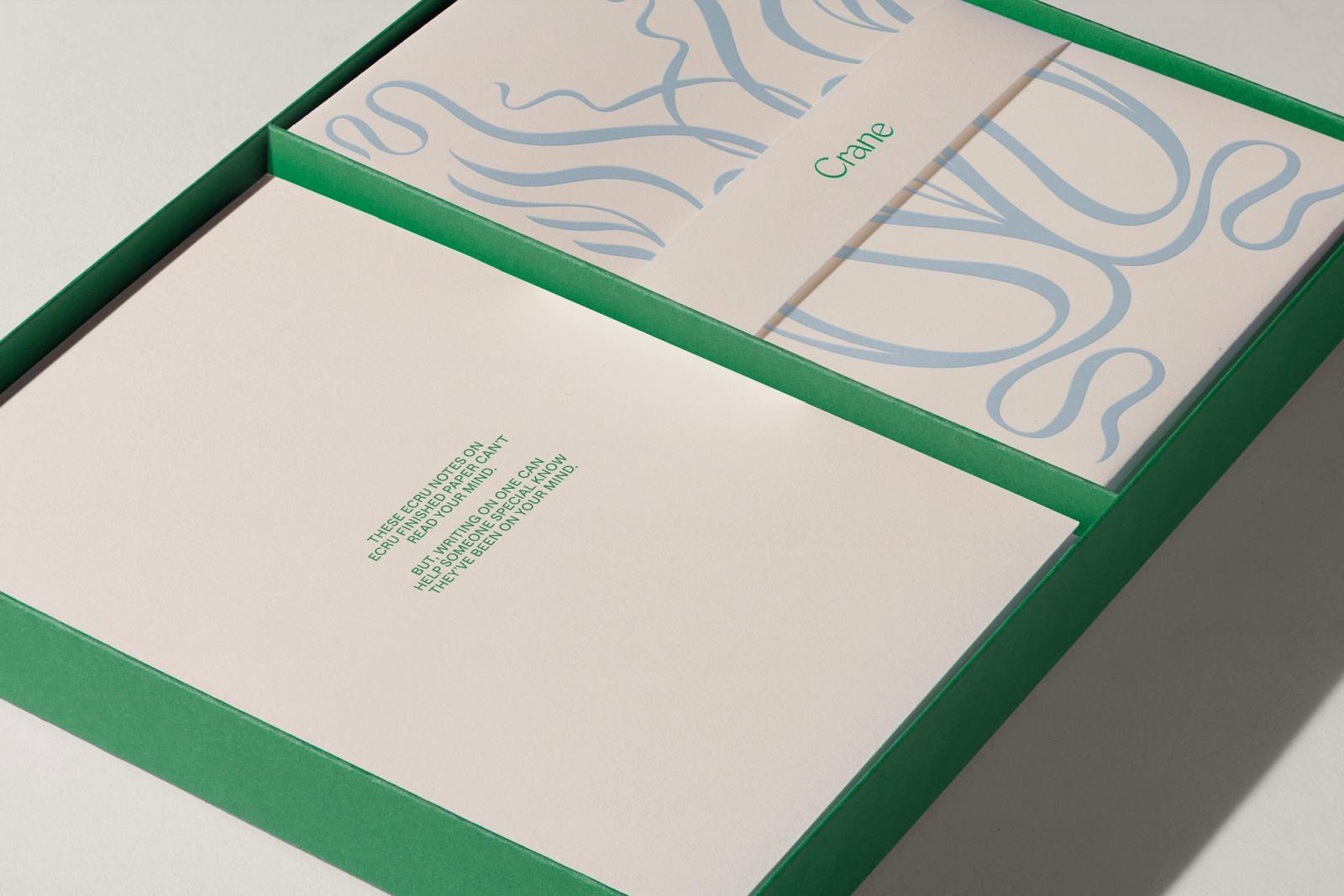 Green Crane tray opened to reveal ecru notes stamped with green typography and pale blue scrollwork belly band