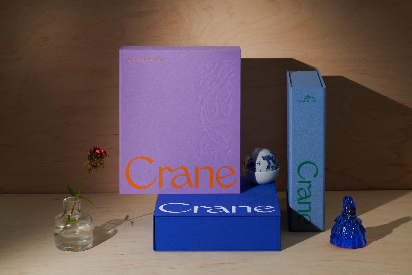Lavender, slate blue, and cobalt blue Crane Classics Collection rigid boxes stacked on birch wood