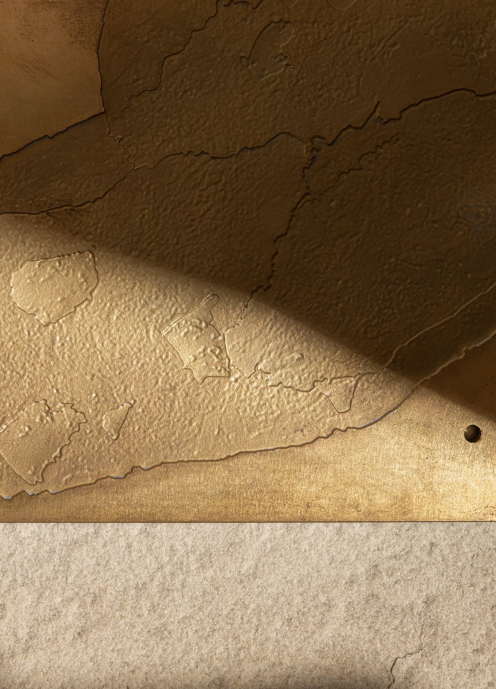Textured surface detail of cast bronze geological map plate — branding by Two Times Elliott