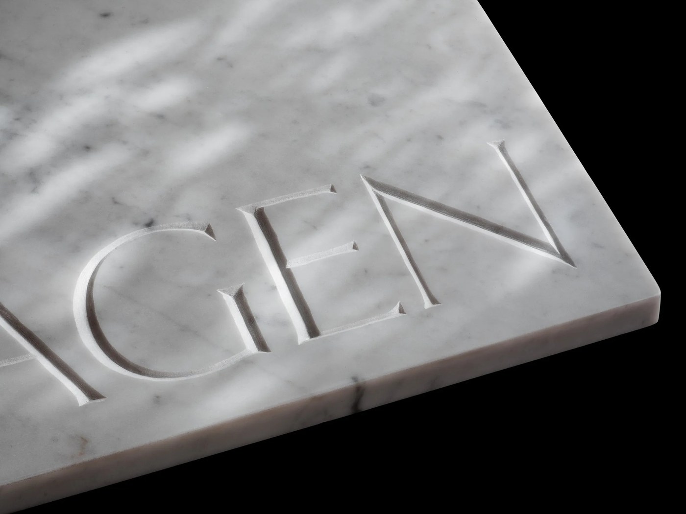 Macro detail of V-cut incised letterforms in Carrara marble — typography by Letters from Sweden