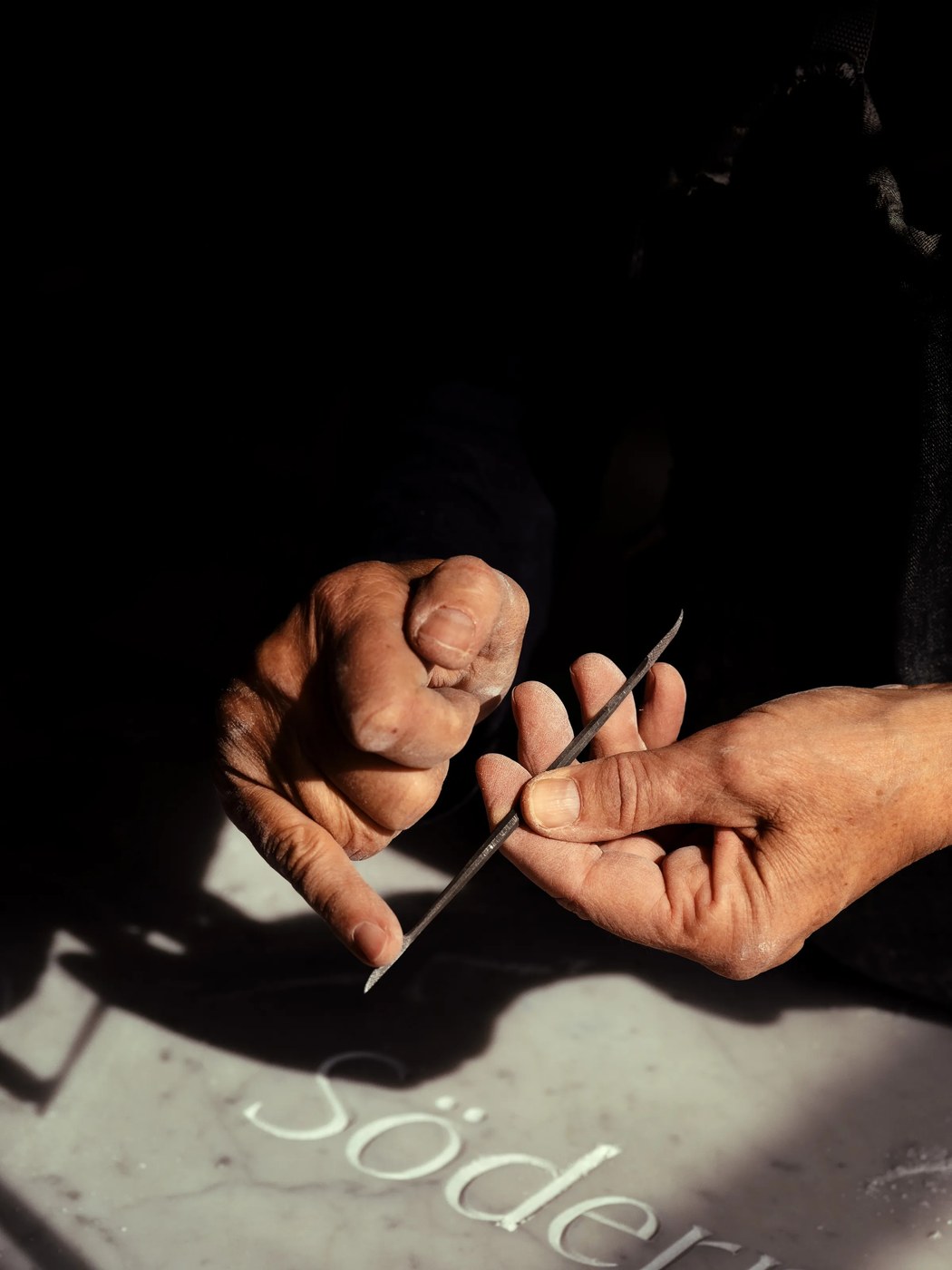 Stone carver with mallet and chisel in Pietrasanta workshop — typography by Letters from Sweden