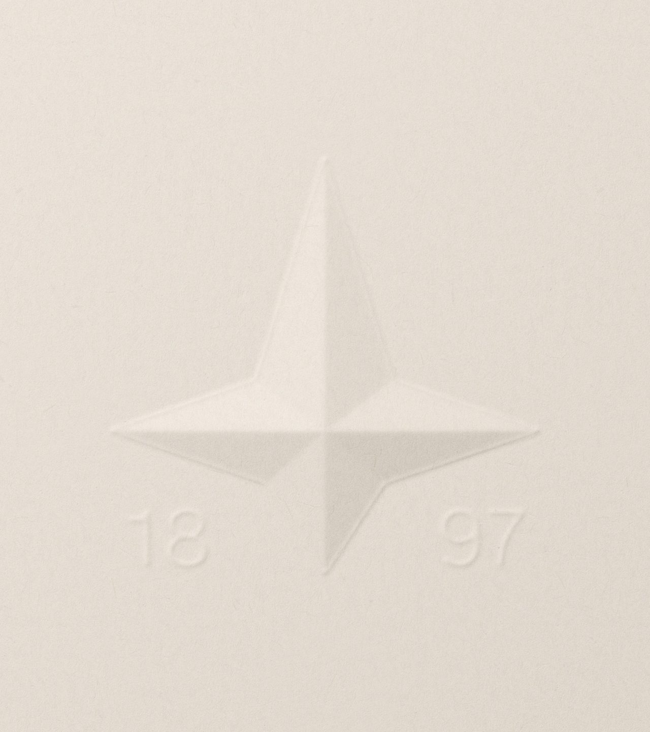 Macro detail of the blind-debossed 1897 four-pointed North Star compass logo symbol on uncoated off-white cotton paper — brand identity by Ragged Edge