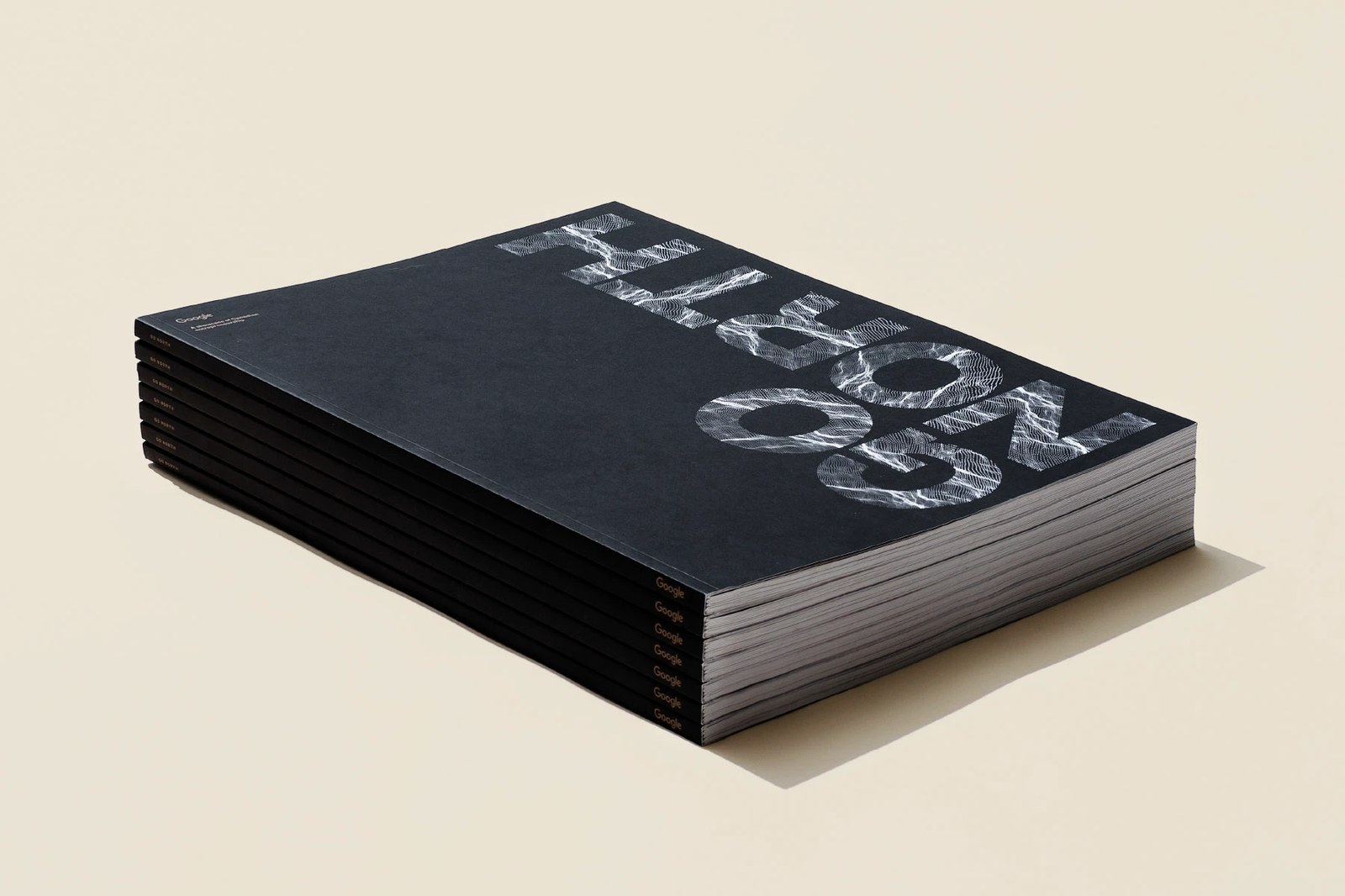 Stack of matte black Google Go North books featuring wireframe contour cover lettering — editorial design by Underline Studio