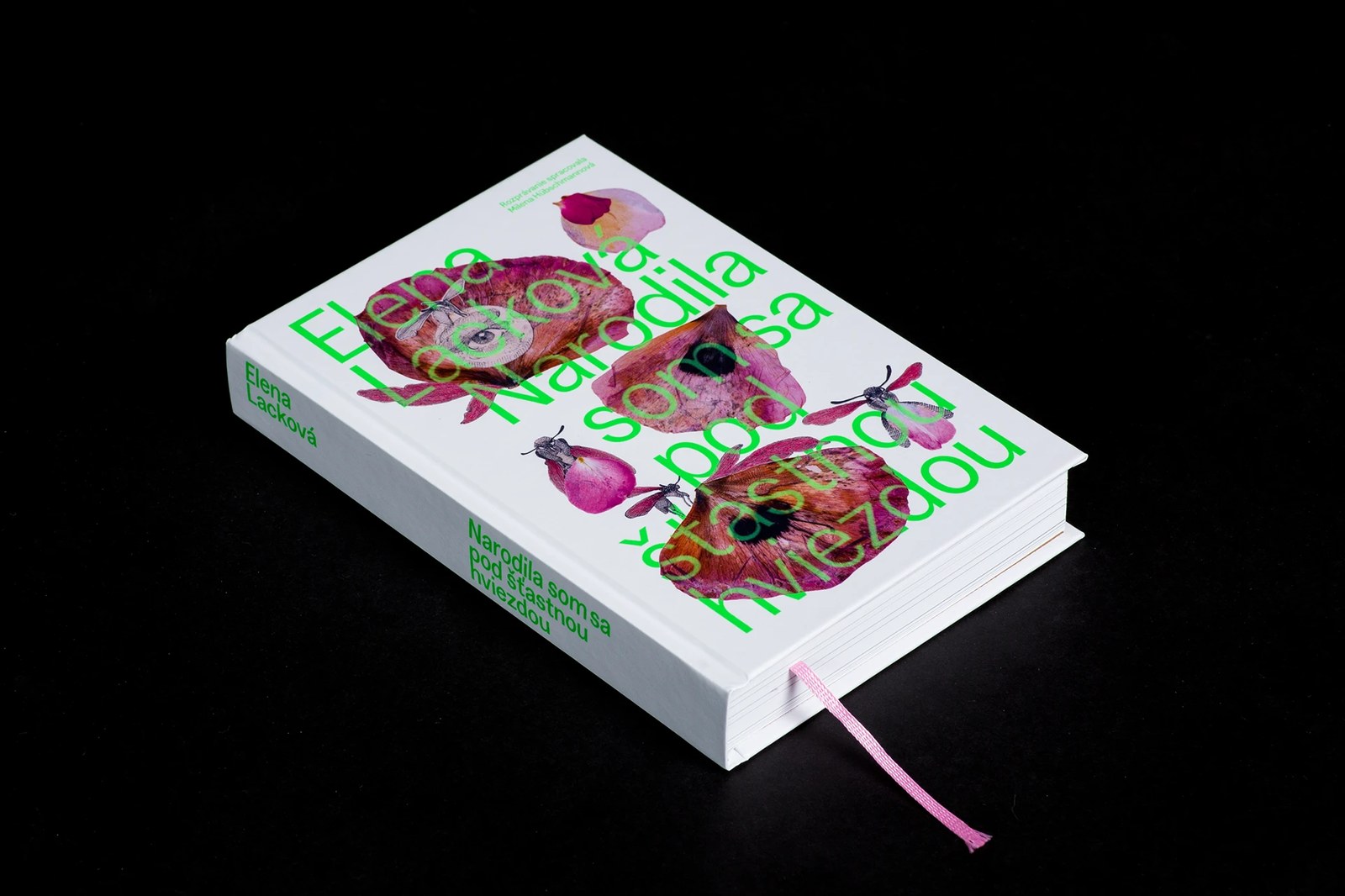 Physical book design detail highlighting matte white hardcover boards, spine typography, and pastel pink woven ribbon marker
