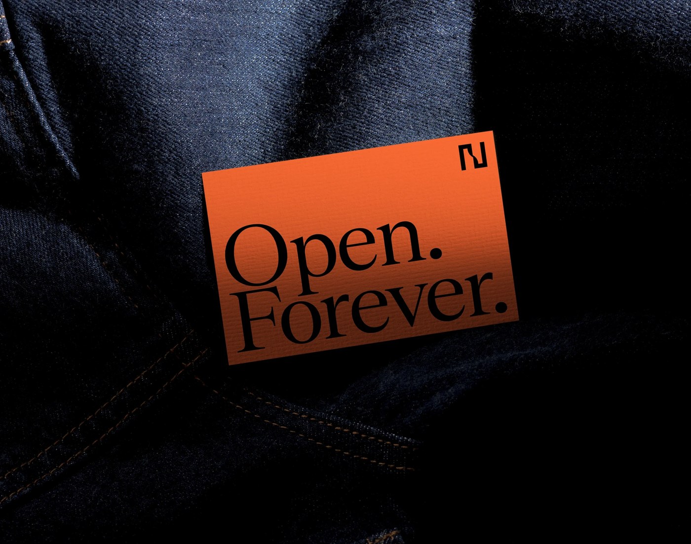 Orange collateral card on raw denim in Node brand identity system