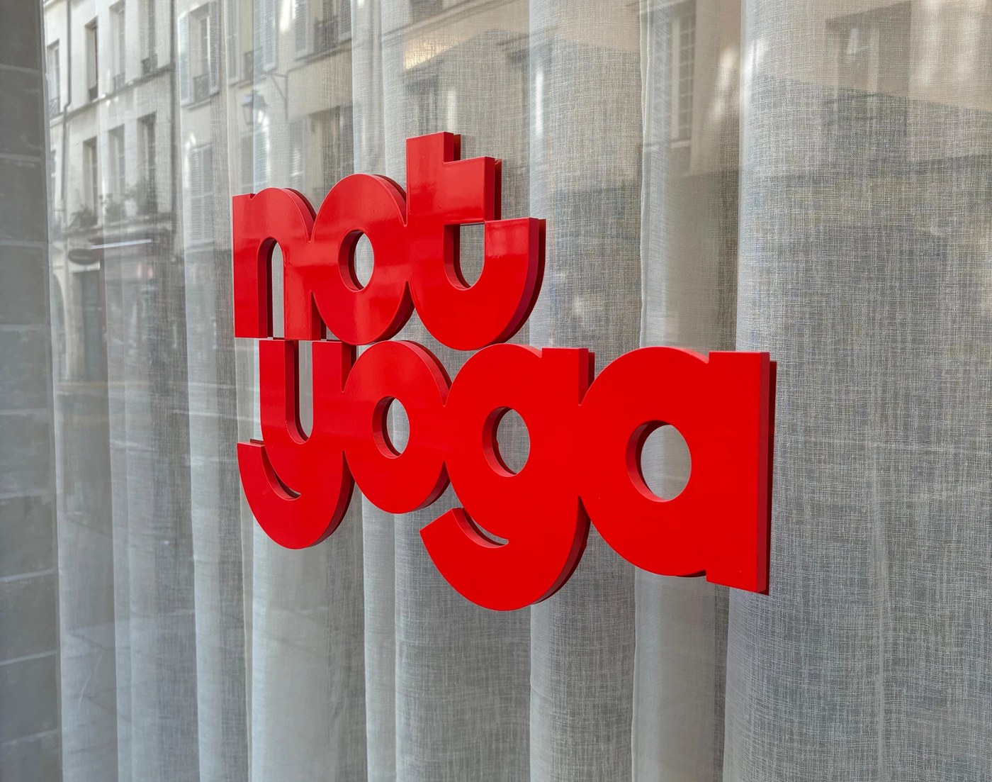 dimensional red acrylic sign mounted on window for Not Yoga Paris studio