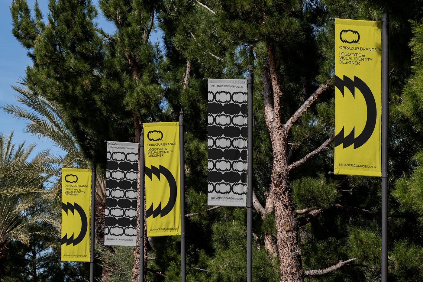 Environmental wayfinding banners with kinetic pattern grids against pine trees