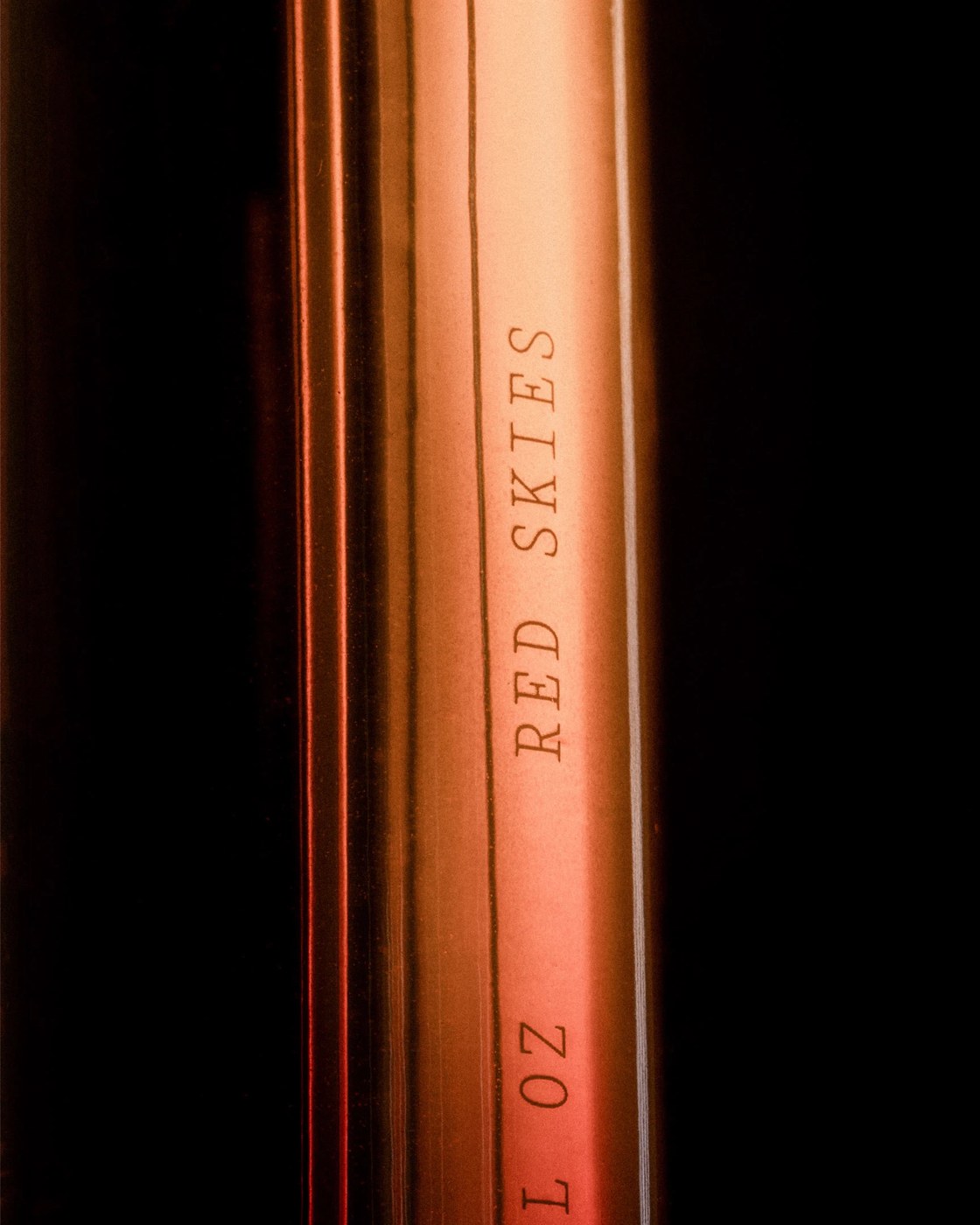 Macro detail of Red Skies fragrance vessel with engraved typography in editorial design by Two Times Elliott