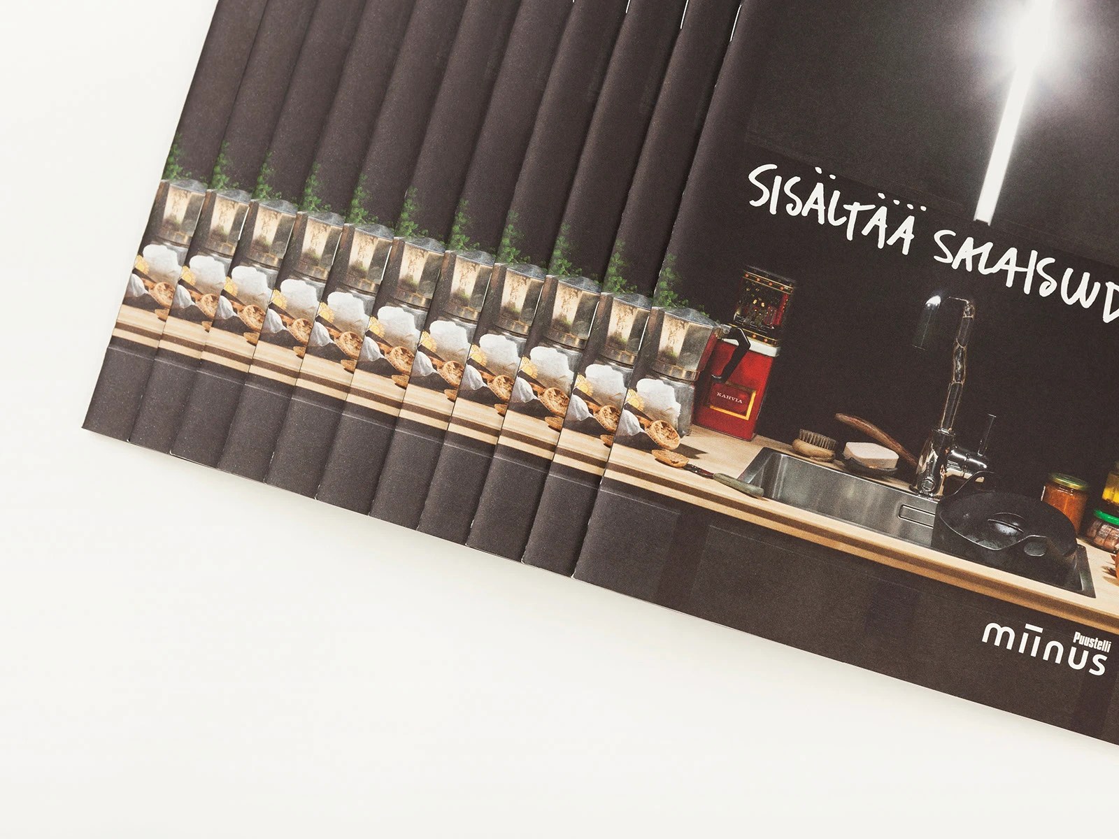 Fanned stack of Puustelli Miinus kitchen brochures with dark wood cabinetry photography and brush-lettered cover titles