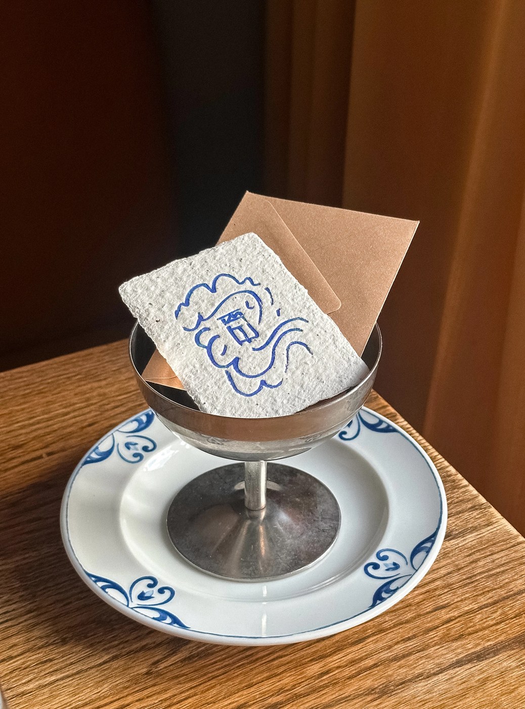 Handmade deckle-edge paper card stamped with blue Elm logo inside a silver coupe