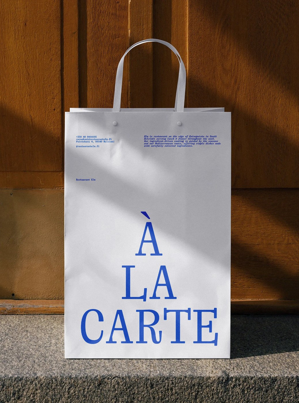 Takeaway paper bag printed with Restaurant Elm dining typography and address