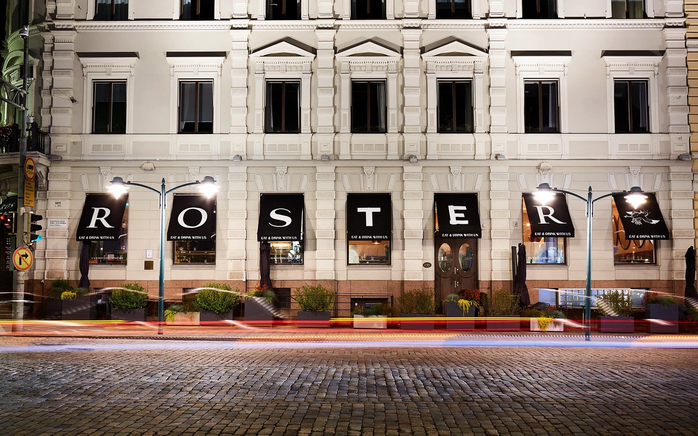 Exterior building facade at dusk in Helsinki displaying black window awnings with custom Roster typography in branding design by BOND