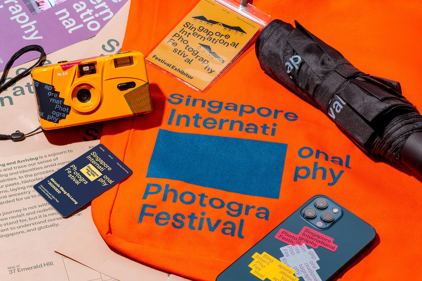 Singapore International Photography Festival graphic design system by Foreign Policy Design with orange tote bag, yellow M35 film camera, passes, and stickers