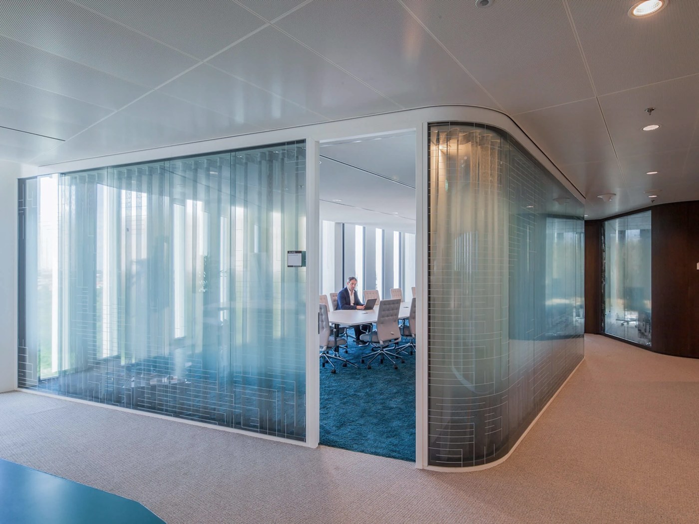 Curved glass conference room showing dual-layer film in spatial design