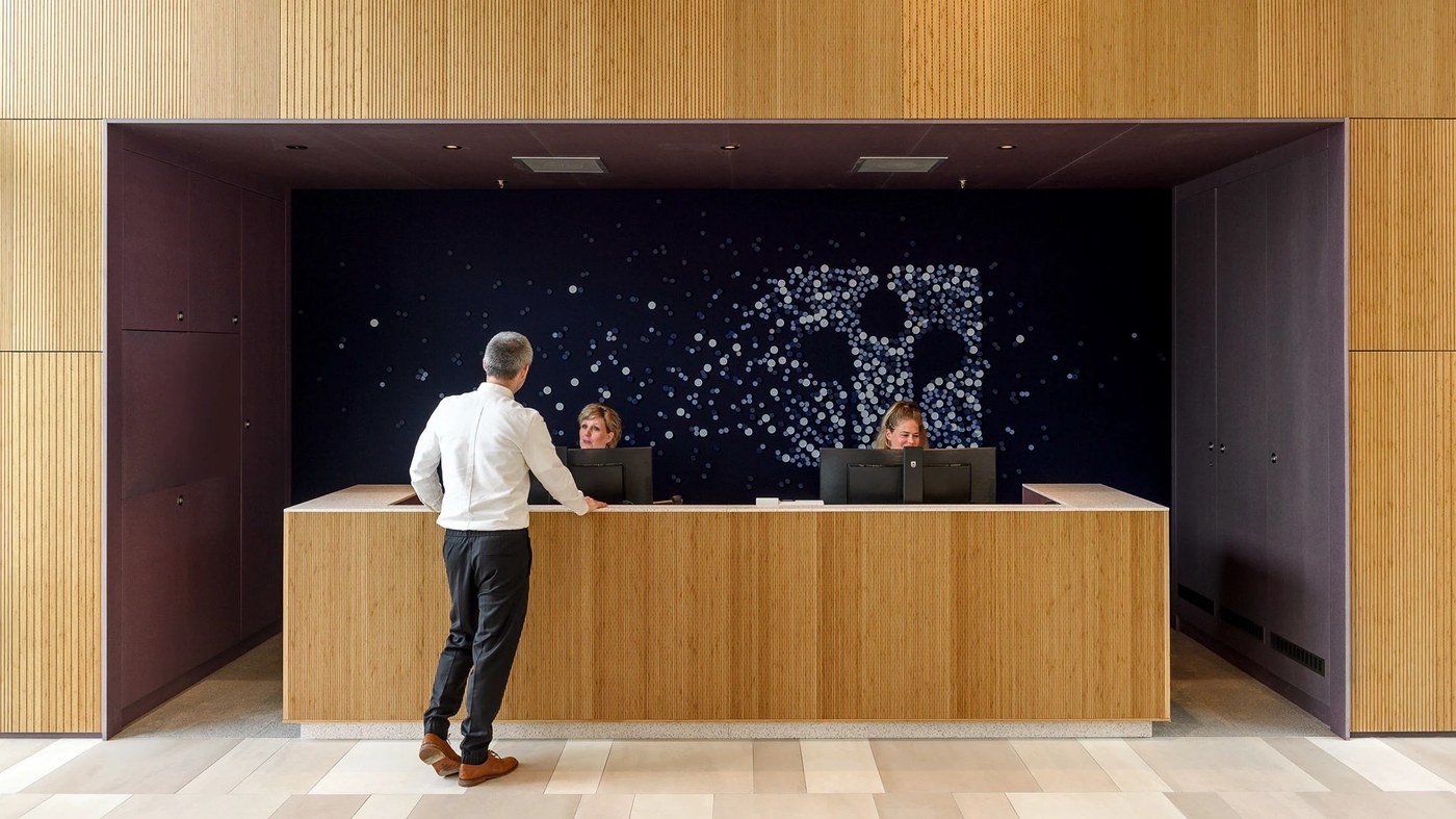 Fluted oak reception desk with acoustic felt realtor seal in spatial design