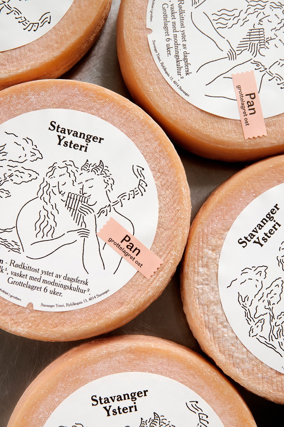Tactile macro detail of round cheese labels showcasing circular embossing, Stavanger Ysteri wordmark, and pink debossed sticker tag in packaging design