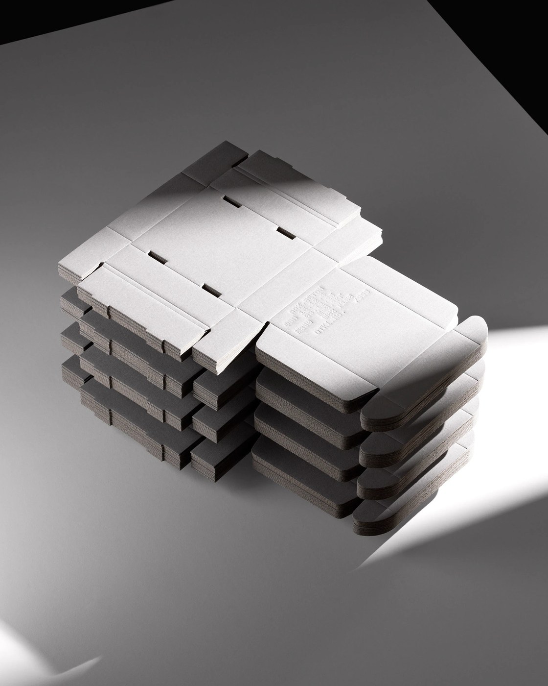 Stack of die-cut structural paperboard box blanks showing tactile packaging design
