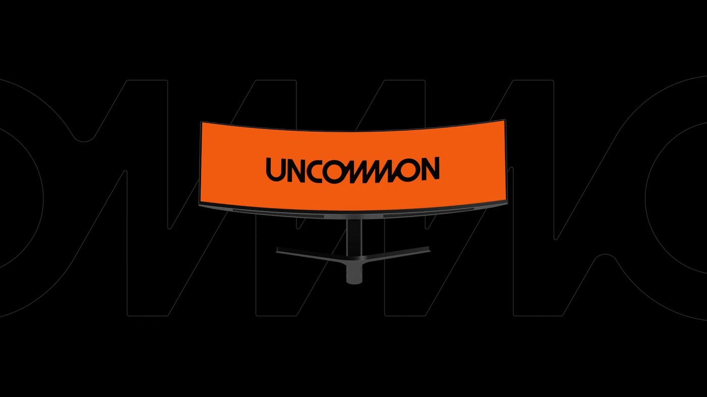 Uncommon brand identity curved ultrawide monitor displaying orange lockup against outlined typography