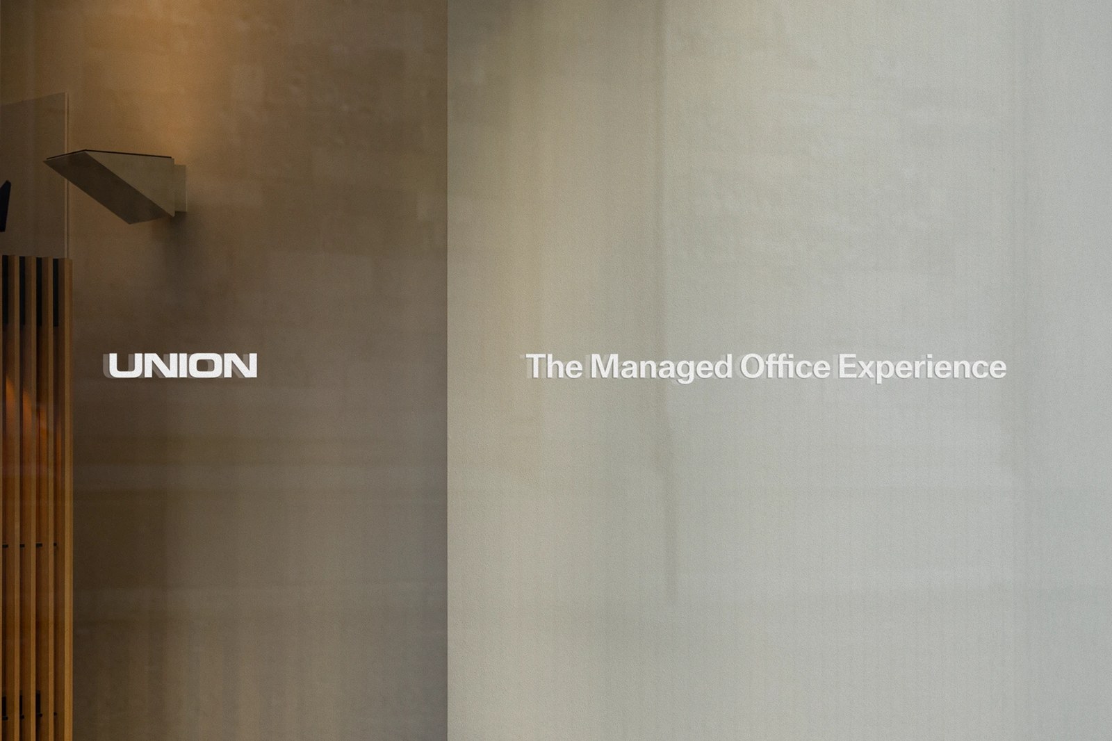 Interior glass partition signage displaying Union and The Managed Office Experience beside slatted wood walls