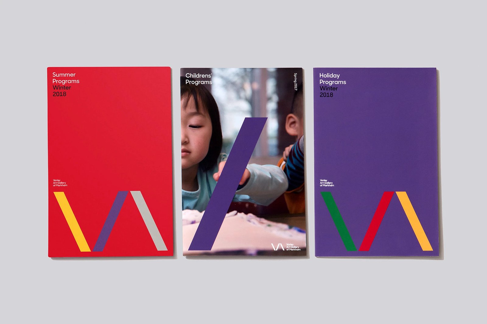 Varley Art Gallery identity flat lay of three seasonal program covers showing the VA logo monogram and sans-serif typography by Underline Studio