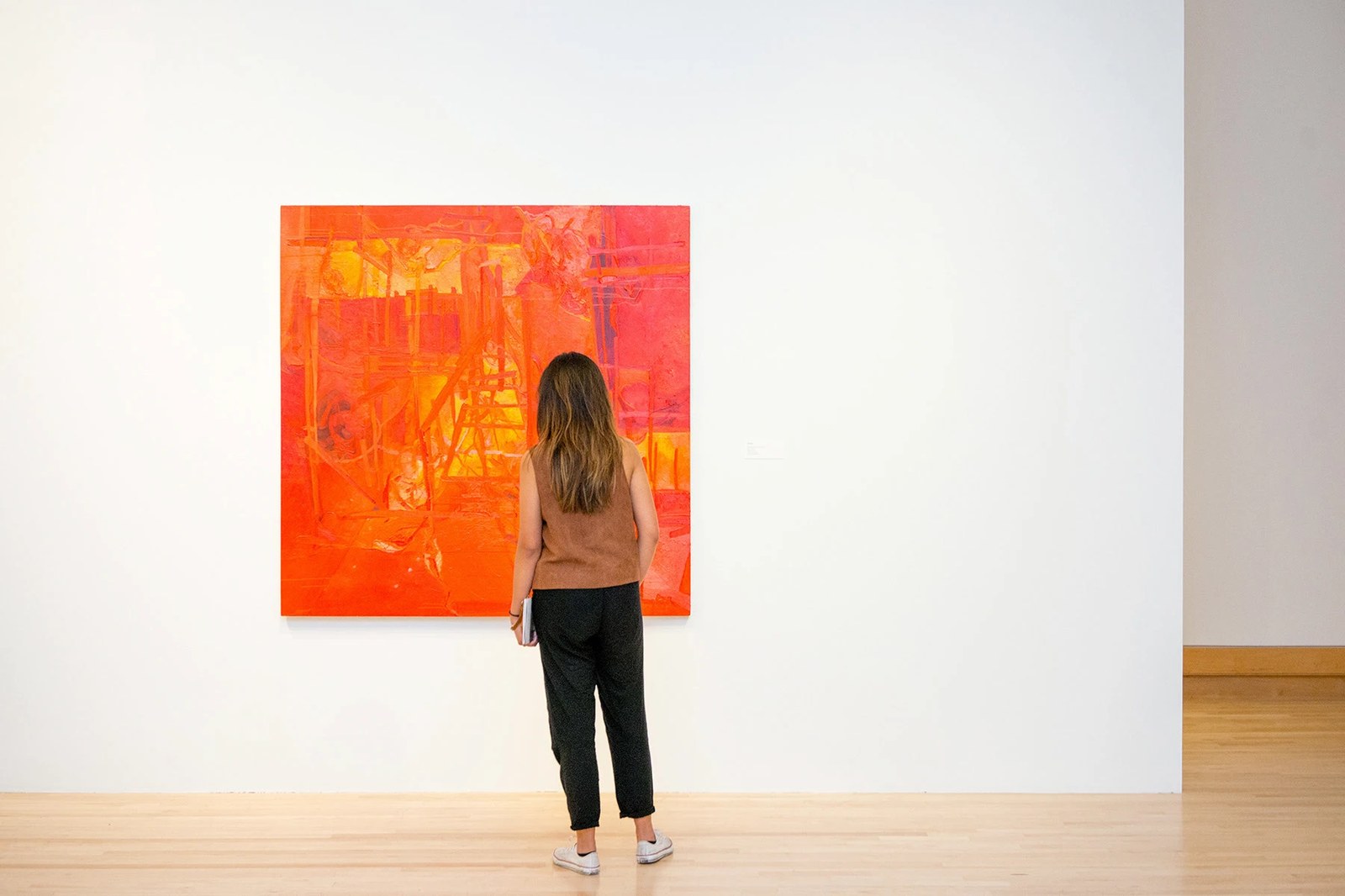 Exhibition view inside Varley Art Gallery with a visitor standing before a square vermilion painting