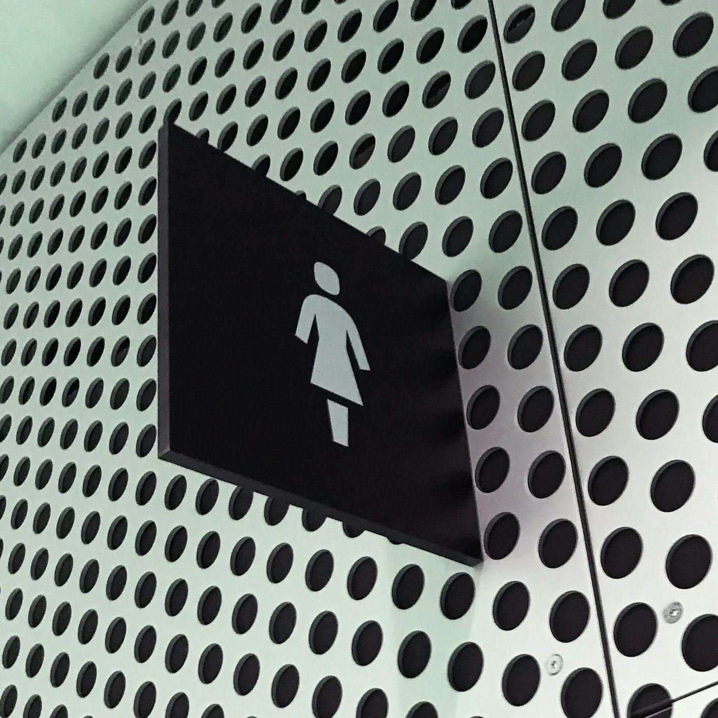 Projecting black blade sign mounted on perforated panels in spatial design by Silo