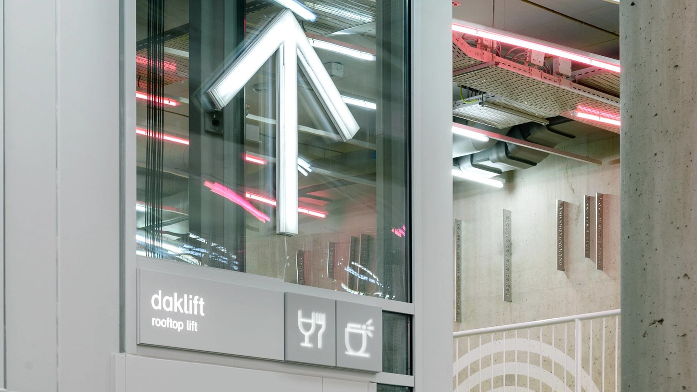 Illuminated elevator arrow and rooftop lift signage in spatial design by Silo