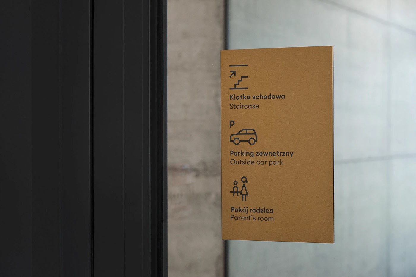 Spatial design ochre metal informational plaque mounted on glass door for FORMAT by Blank Studio
