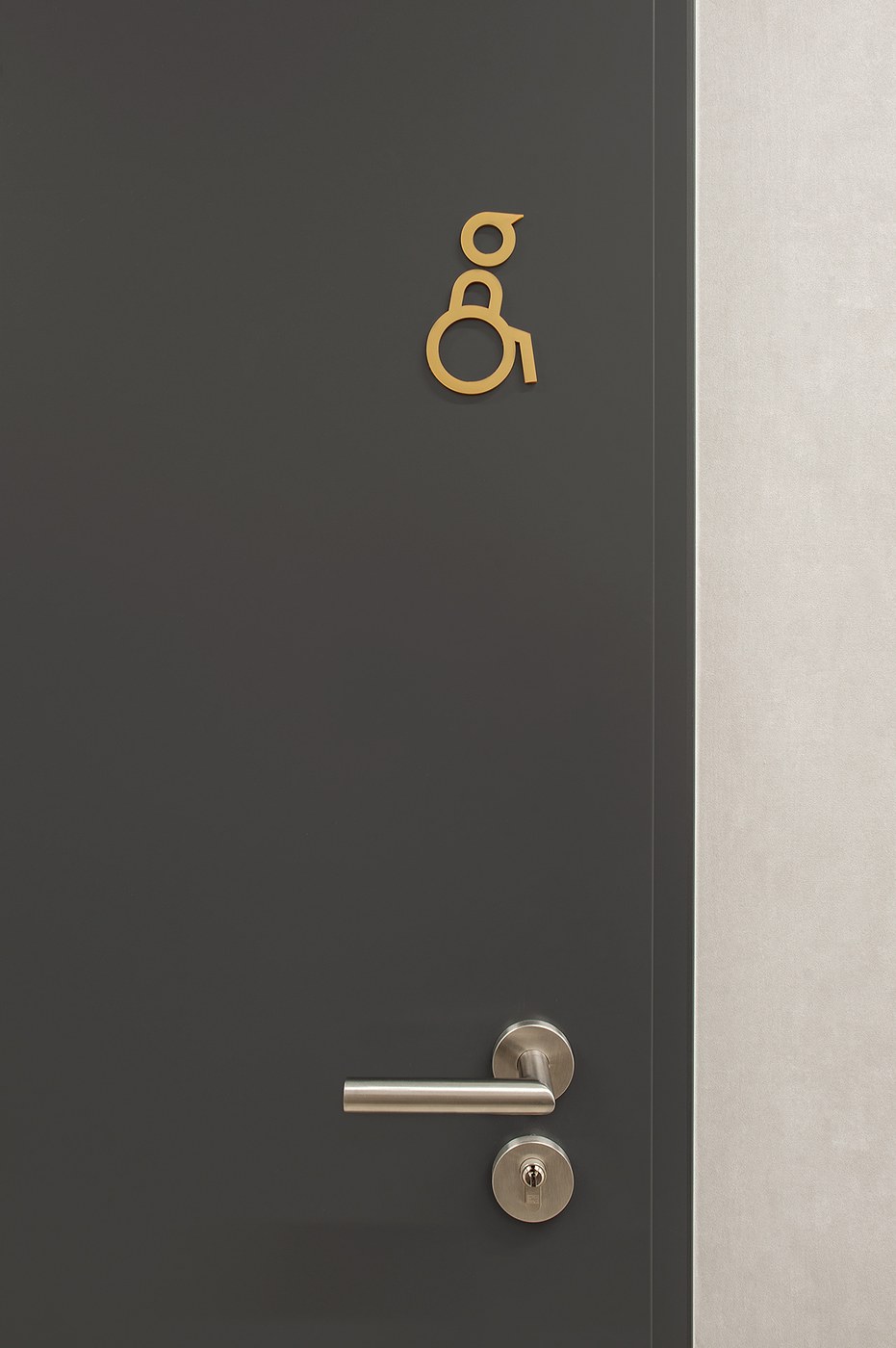 Spatial design accessible restroom pictogram in ochre on charcoal door for FORMAT by Blank Studio