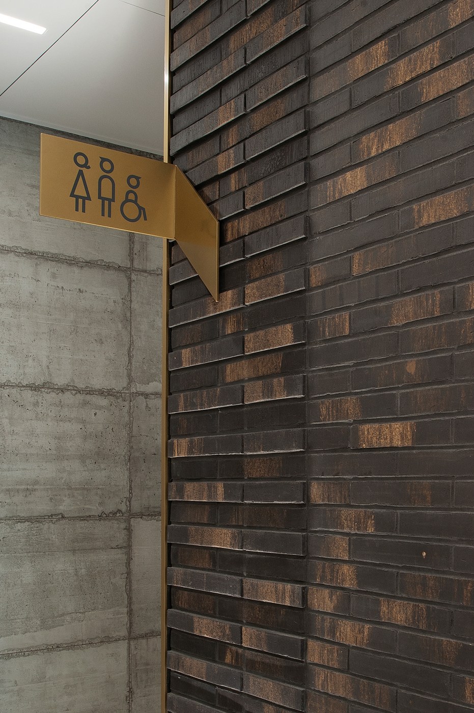 Spatial design folded brass cantilevered flag sign on clinker wall for FORMAT by Blank Studio
