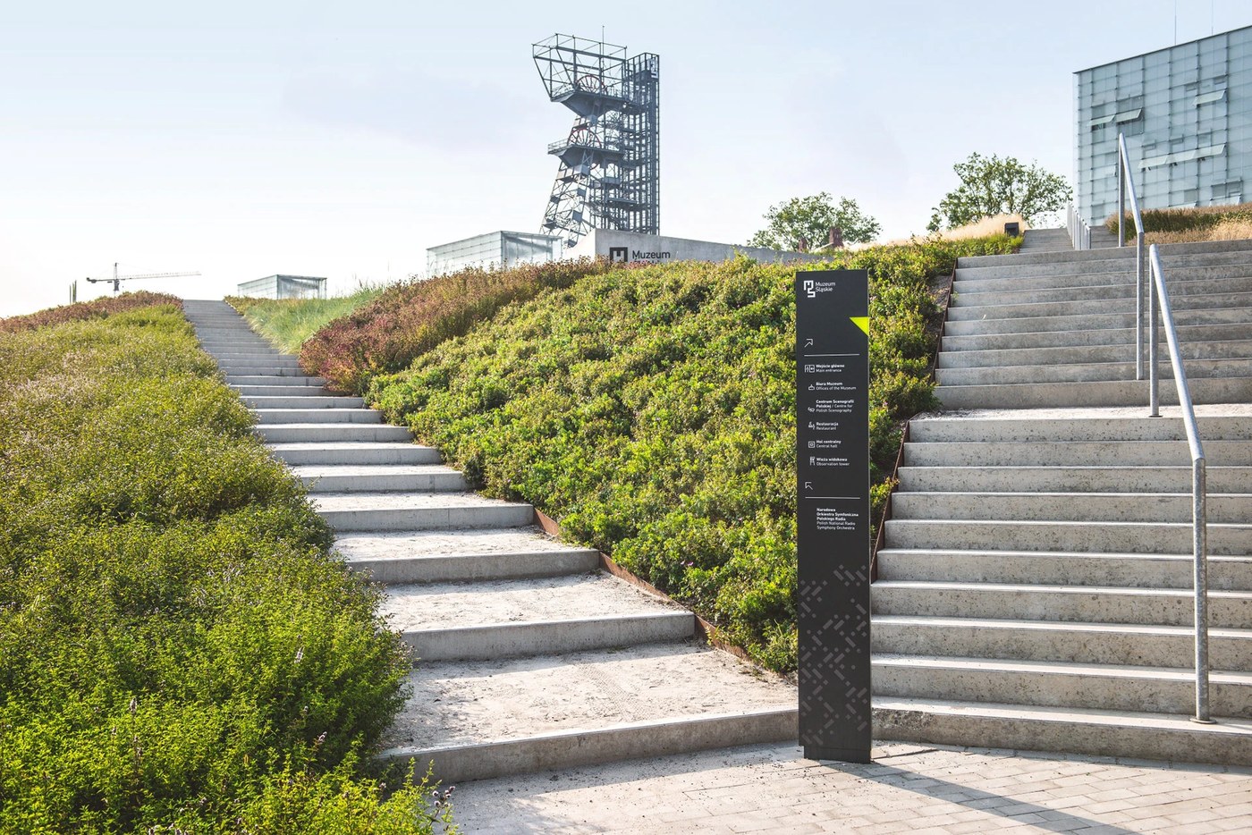 Matte anthracite directional totem standing between concrete stairways showcasing spatial design at the Silesian Museum