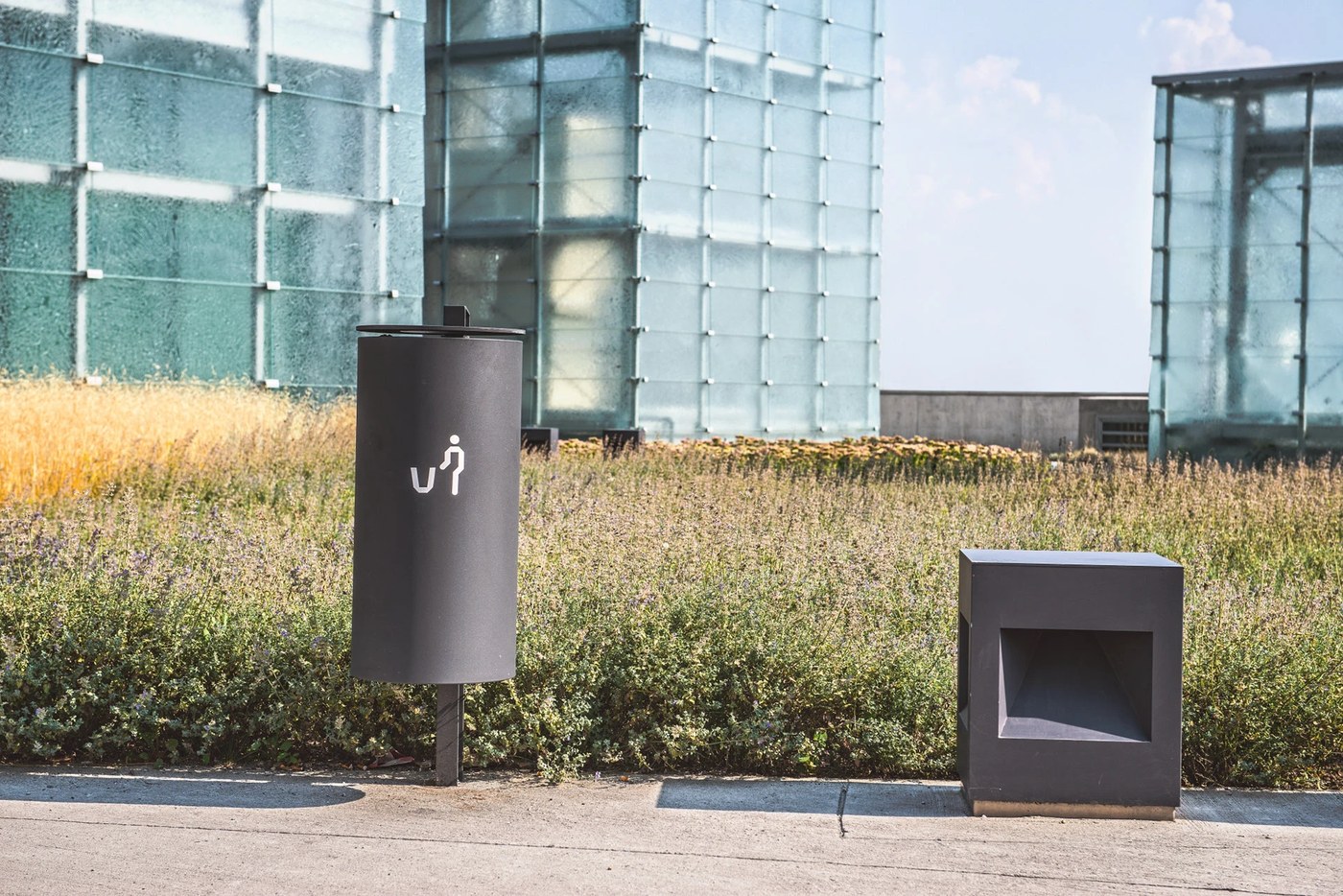 Anthracite steel waste receptacle with minimalist figure pictogram demonstrating comprehensive spatial design