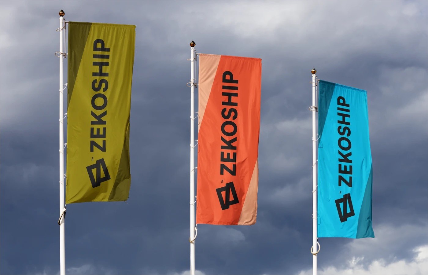 Three vertical outdoor flagpole banners in olive gold, coral orange, and electric cyan against storm clouds