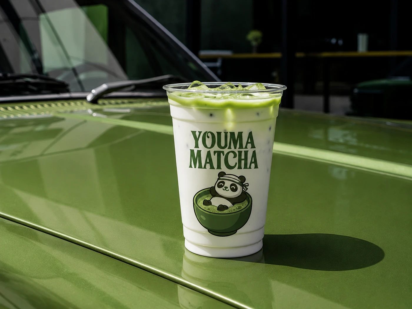 Youma Matcha branding iced beverage cup on green bonnet