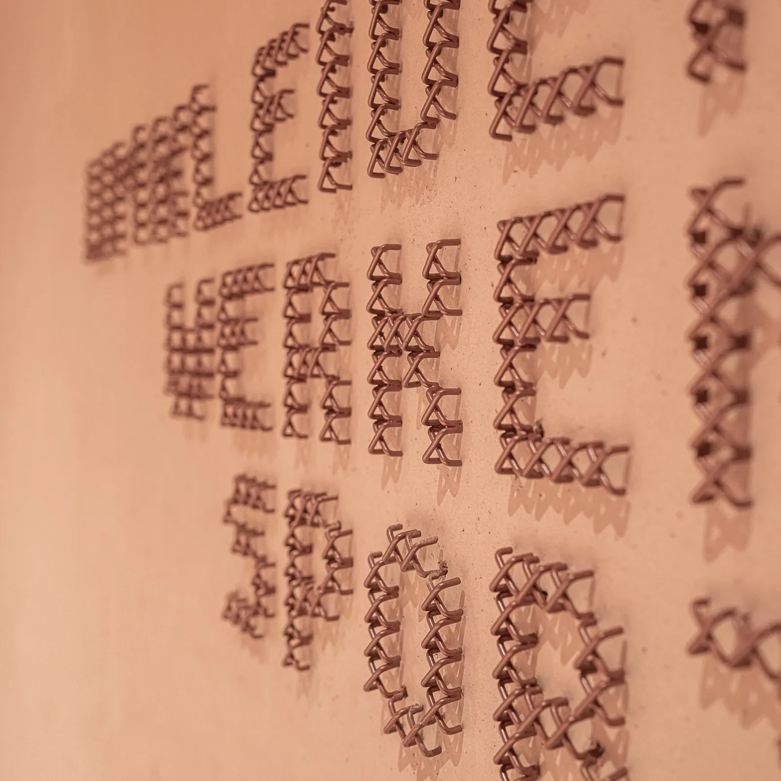 Copper cross-stitch wayfinding lettering in macro at Education Center Kössen